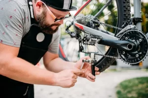 Bicycle mechanic in apron adjusts bike chain